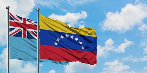 Fiji and Venezuela flag waving in the wind against white cloudy blue sky together. Diplomacy concept, international relations.