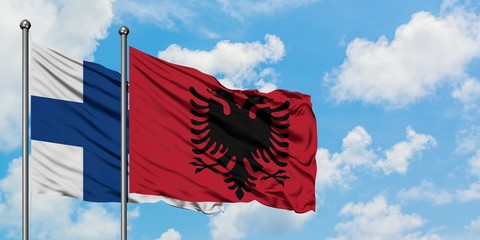 Finland and Albania flag waving in the wind against white cloudy blue sky together. Diplomacy...