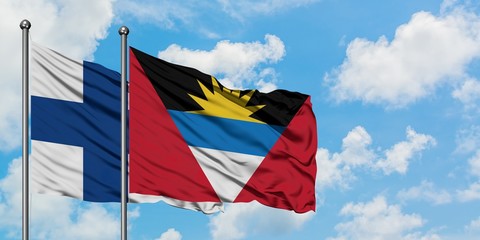 Finland and Antigua and Barbuda flag waving in the wind against white cloudy blue sky together. Diplomacy concept, international relations.