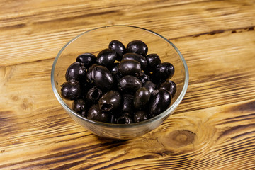 Pickled black olives in glass bowl on wooden table