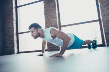 Fototapeta premium Profile photo of macho sportsman guy do push ups plank hands leaning floor determined trainer sportswear tank-top shorts sneakers training house studio windows indoors
