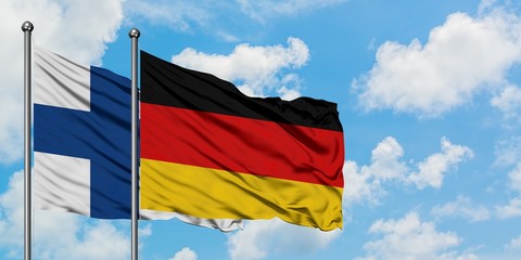 Finland and Germany flag waving in the wind against white cloudy blue sky together. Diplomacy concept, international relations.