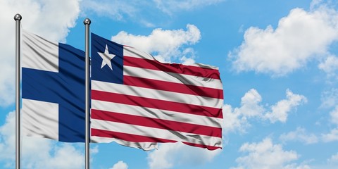 Finland and Liberia flag waving in the wind against white cloudy blue sky together. Diplomacy concept, international relations.