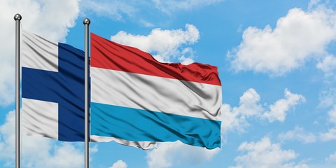 Finland and Luxembourg flag waving in the wind against white cloudy blue sky together. Diplomacy concept, international relations.