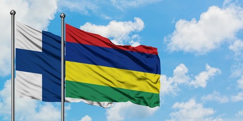 Finland and Mauritius flag waving in the wind against white cloudy blue sky together. Diplomacy...