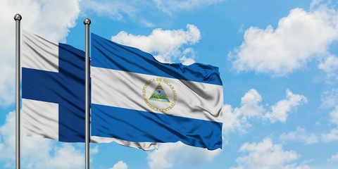 Finland and Nicaragua flag waving in the wind against white cloudy blue sky together. Diplomacy...