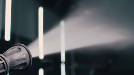 Water hose car washing close up. Worker man watering with foam auto out of manually high pressure...
