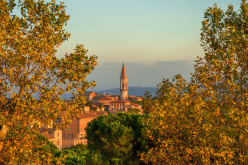 Autumn in Perugia. View of the beautiful Perugia medieval historic center and Umbria countryside with the iconic St Peter hexagonal belltower and autumnal leaves at sunset