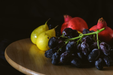 still life pears and black grapes on a black background