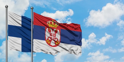 Finland and Serbia flag waving in the wind against white cloudy blue sky together. Diplomacy concept, international relations.