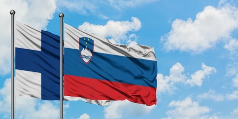 Finland and Slovenia flag waving in the wind against white cloudy blue sky together. Diplomacy concept, international relations.