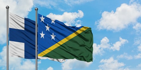 Finland and Solomon Islands flag waving in the wind against white cloudy blue sky together. Diplomacy concept, international relations.