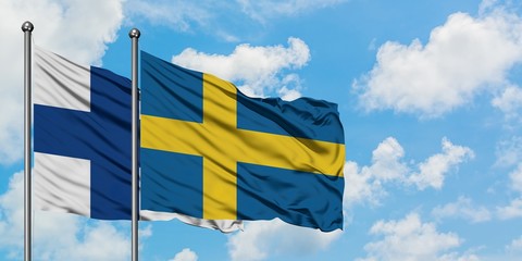 Finland and Sweden flag waving in the wind against white cloudy blue sky together. Diplomacy concept, international relations.