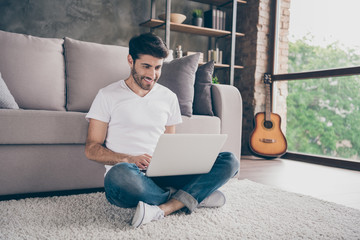 Photo of mixed race arabian guy sitting cozy floor carpet near sofa holding notebook speaking skype with relatives wear casual outfit flat loft living room indoors