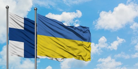 Finland and Ukraine flag waving in the wind against white cloudy blue sky together. Diplomacy concept, international relations.