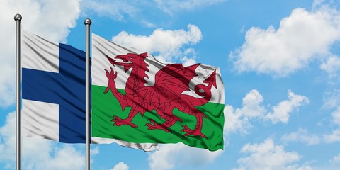 Finland and Wales flag waving in the wind against white cloudy blue sky together. Diplomacy...