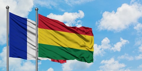 France and Bolivia flag waving in the wind against white cloudy blue sky together. Diplomacy concept, international relations.
