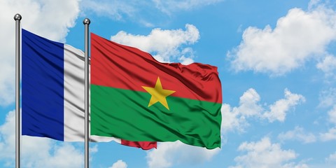 France and Burkina Faso flag waving in the wind against white cloudy blue sky together. Diplomacy concept, international relations.