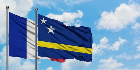 France and Curacao flag waving in the wind against white cloudy blue sky together. Diplomacy concept, international relations.