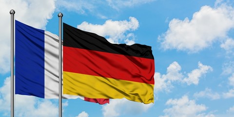 France and Germany flag waving in the wind against white cloudy blue sky together. Diplomacy concept, international relations.