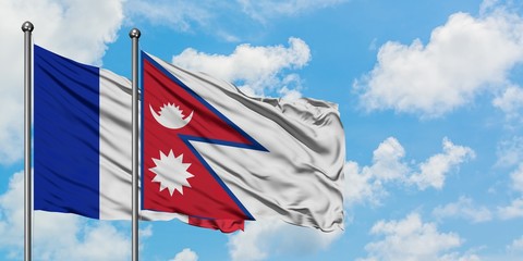 France and Nepal flag waving in the wind against white cloudy blue sky together. Diplomacy concept, international relations.