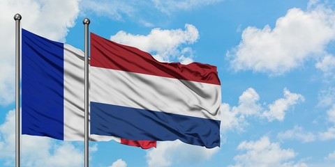 France and Netherlands flag waving in the wind against white cloudy blue sky together. Diplomacy concept, international relations.
