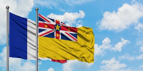 France and Niue flag waving in the wind against white cloudy blue sky together. Diplomacy concept, international relations.
