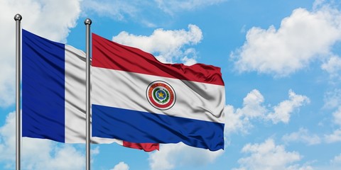 France and Paraguay flag waving in the wind against white cloudy blue sky together. Diplomacy concept, international relations.