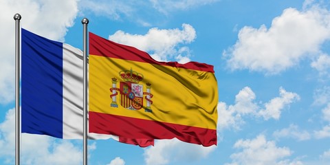 France and Spain flag waving in the wind against white cloudy blue sky together. Diplomacy concept, international relations.