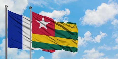 France and Togo flag waving in the wind against white cloudy blue sky together. Diplomacy concept, international relations.