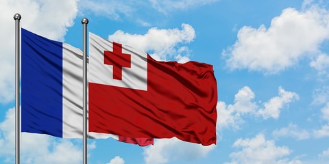 France and Tonga flag waving in the wind against white cloudy blue sky together. Diplomacy concept, international relations.