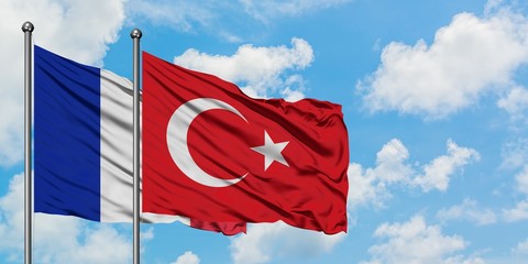 France and Turkey flag waving in the wind against white cloudy blue sky together. Diplomacy concept, international relations.