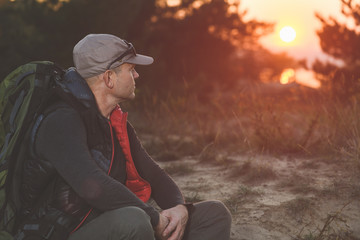 Fototapeta na wymiar Hiker with big backpack sit down against sunset