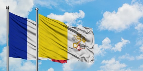 France and Vatican City flag waving in the wind against white cloudy blue sky together. Diplomacy concept, international relations.