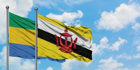 Gabon and Brunei flag waving in the wind against white cloudy blue sky together. Diplomacy concept,...
