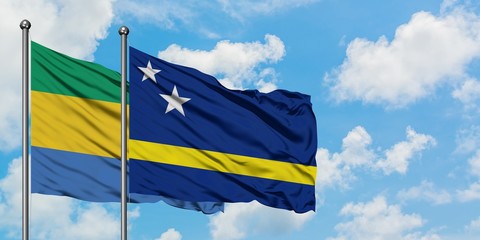 Gabon and Curacao flag waving in the wind against white cloudy blue sky together. Diplomacy...
