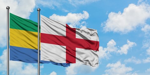 Gabon and England flag waving in the wind against white cloudy blue sky together. Diplomacy concept, international relations.