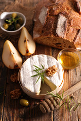 french cheese with bread, honey and pear on wood background