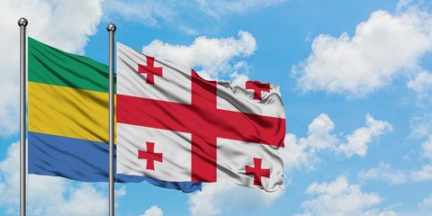 Gabon and Georgia flag waving in the wind against white cloudy blue sky together. Diplomacy...