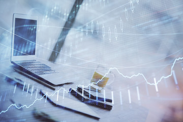 Forex graph hologram on table with computer background. Multi exposure. Concept of financial markets.