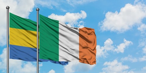 Gabon and Ireland flag waving in the wind against white cloudy blue sky together. Diplomacy...