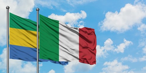 Gabon and Italy flag waving in the wind against white cloudy blue sky together. Diplomacy concept,...