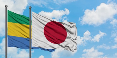 Fototapeta na wymiar Gabon and Japan flag waving in the wind against white cloudy blue sky together. Diplomacy concept, international relations.
