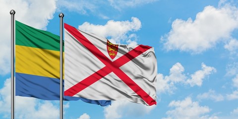 Gabon and Jersey flag waving in the wind against white cloudy blue sky together. Diplomacy concept, international relations.