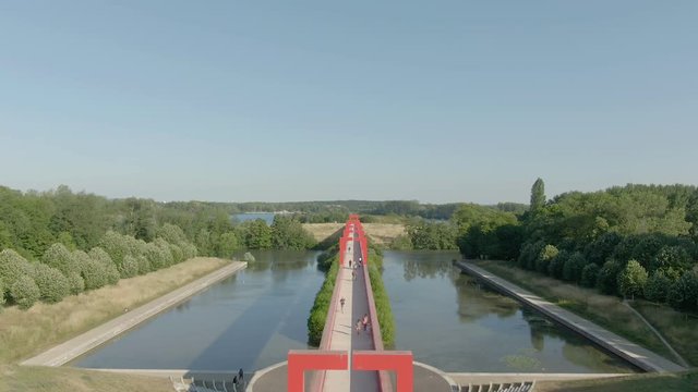 Modern architectural complex in the city of Cergy on the Oise River, France. Aerial shot of a conceptual bridge with red arches. Beautiful play of light and shadow