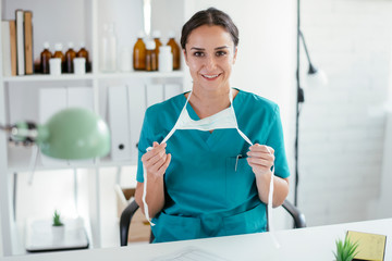 Young female doctor in medical office. Beautiful female doctor putting mask on.