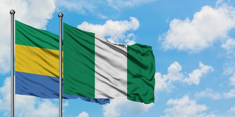 Gabon and Nigeria flag waving in the wind against white cloudy blue sky together. Diplomacy...
