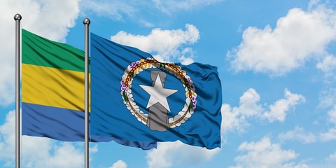 Gabon and Northern Mariana Islands flag waving in the wind against white cloudy blue sky together....