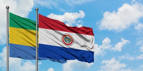 Gabon and Paraguay flag waving in the wind against white cloudy blue sky together. Diplomacy concept, international relations.
