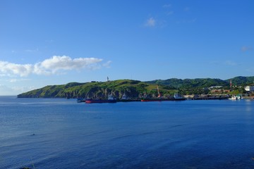 A seaport backdropped with blue sky, blue sea and green mountains. Basco, Batanes, Philippines